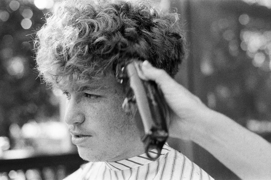 man in white and black stripe shirt holding hair clipper