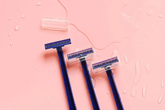 Three blue toothbrushes sitting on top of a pink surface