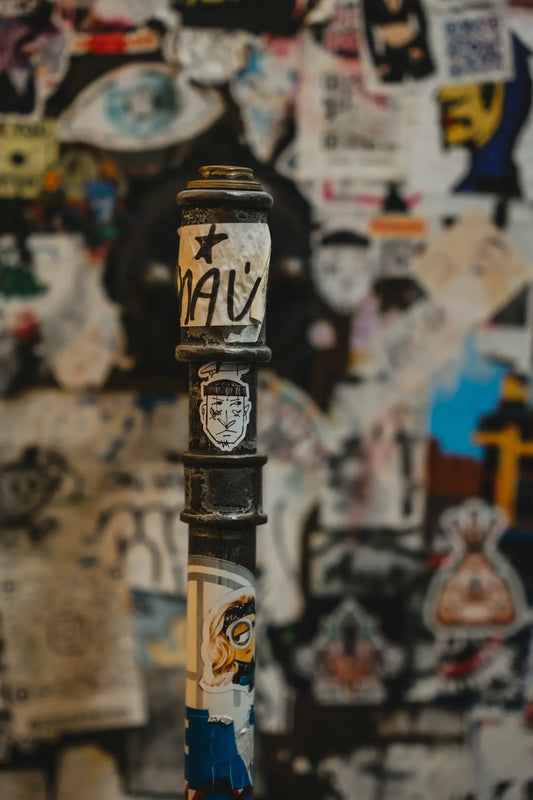 A pole covered in stickers and graffiti art.