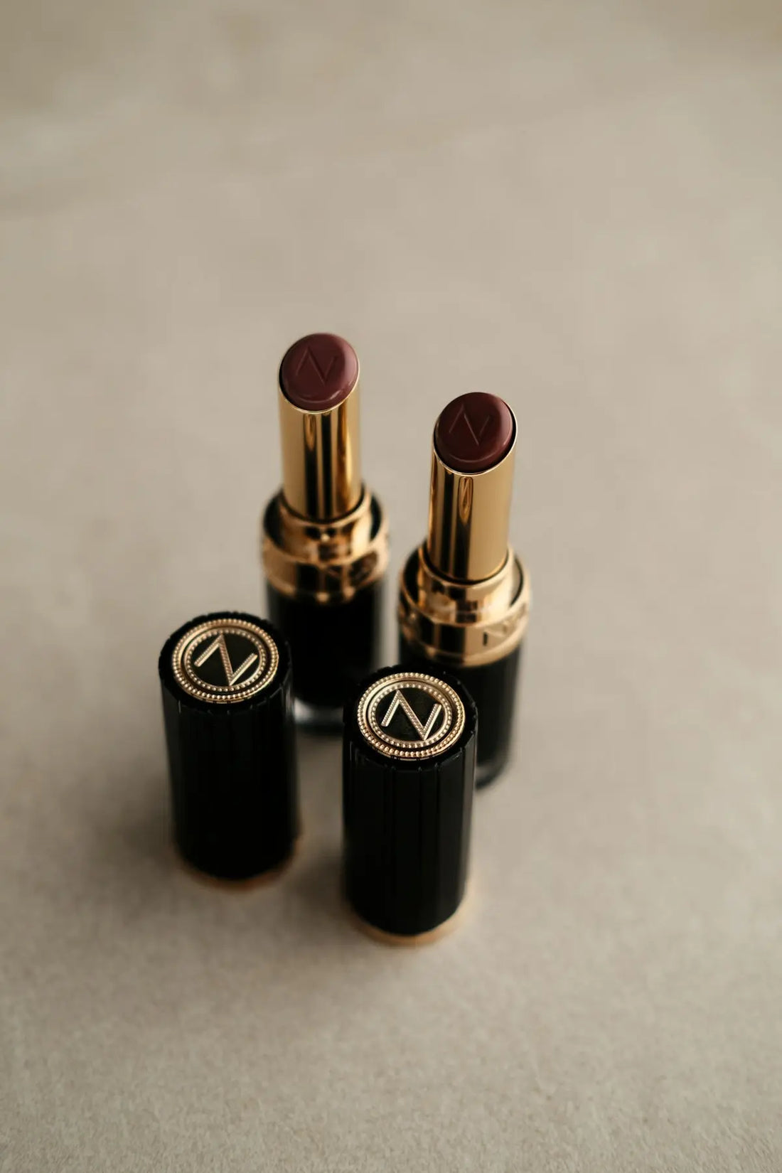 Two dark red lipsticks with gold accents