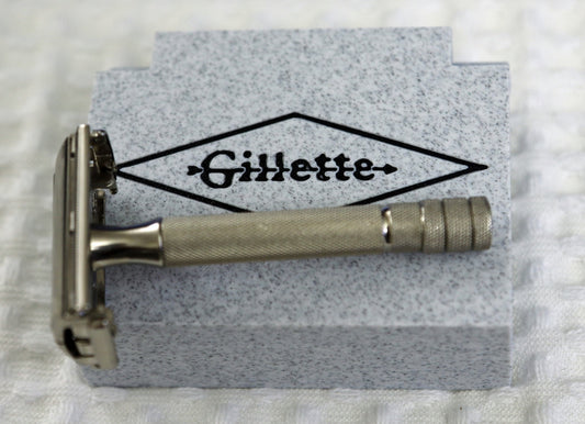 A vintage gillette safety razor rests on a grey box.