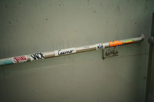 Sticker-covered metal handrail against a plain wall