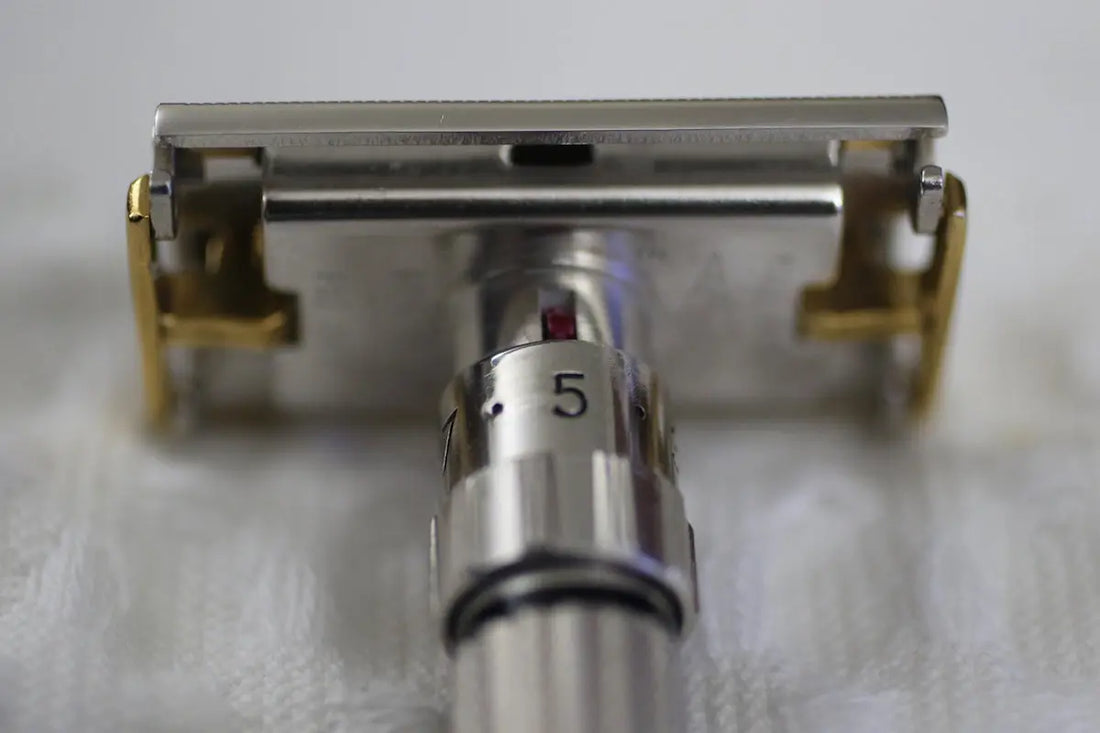 Adjustable safety razor with gold accents on a white surface.