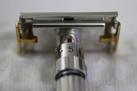 Adjustable safety razor with gold accents on a white surface.