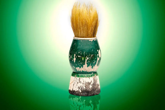 A vintage shaving brush with a distressed green handle.